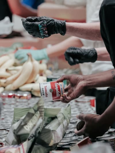 People wearing gloves inspect food (cans, fruit, etc.).